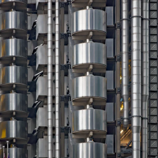 L'architecture mise à nu - Photographie d'art verticale du Lloyd's Building à Londres, gros plan sur les conduits métalliques et modules en acier.