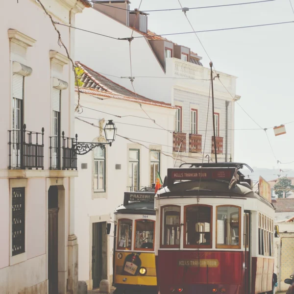 Photographie artistique du Tram 28 se croisant dans une ruelle de l'Alfama à Lisbonne, style vintage et couleurs chaudes.