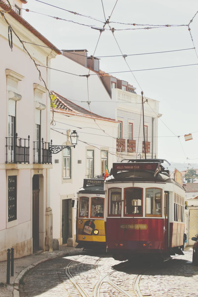 Photographie artistique du Tram 28 se croisant dans une ruelle de l'Alfama à Lisbonne, style vintage et couleurs chaudes.